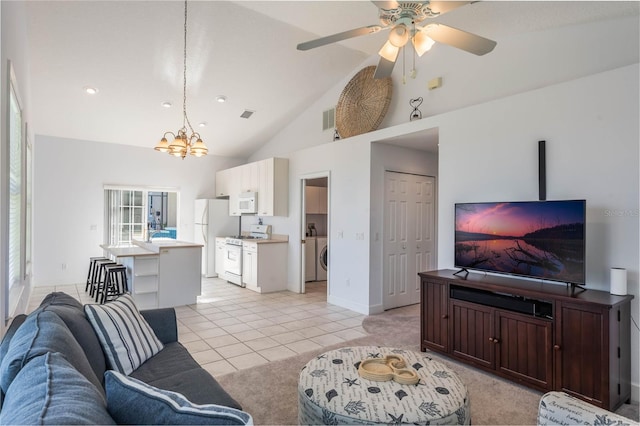 tiled living room featuring ceiling fan with notable chandelier, washer / clothes dryer, and high vaulted ceiling