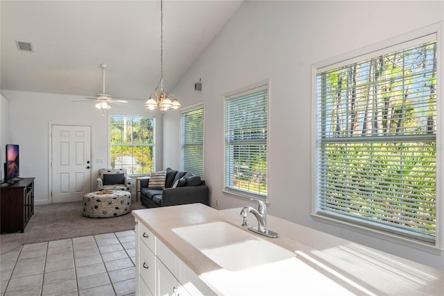 bathroom with tile patterned floors, ceiling fan with notable chandelier, sink, and high vaulted ceiling