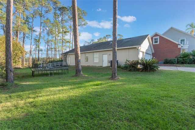 view of side of property with a lawn, a garage, and a trampoline