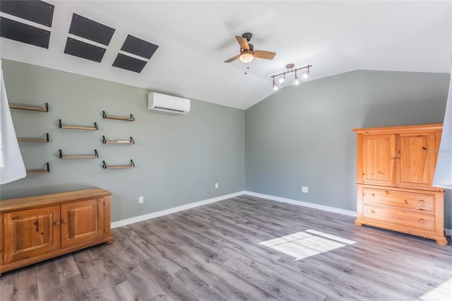 interior space featuring hardwood / wood-style flooring, ceiling fan, a wall unit AC, and vaulted ceiling