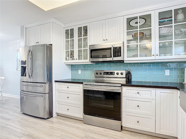 kitchen with stainless steel appliances, white cabinetry, tasteful backsplash, and light wood-type flooring