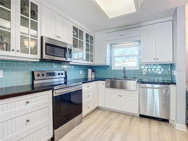 kitchen with sink, light hardwood / wood-style flooring, appliances with stainless steel finishes, backsplash, and white cabinets