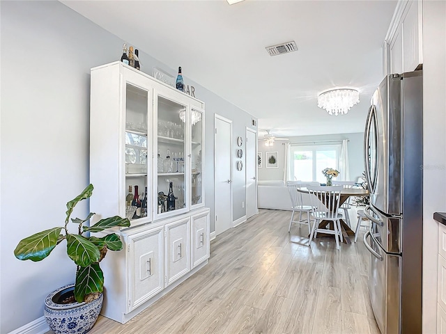 dining room featuring ceiling fan with notable chandelier and light hardwood / wood-style flooring