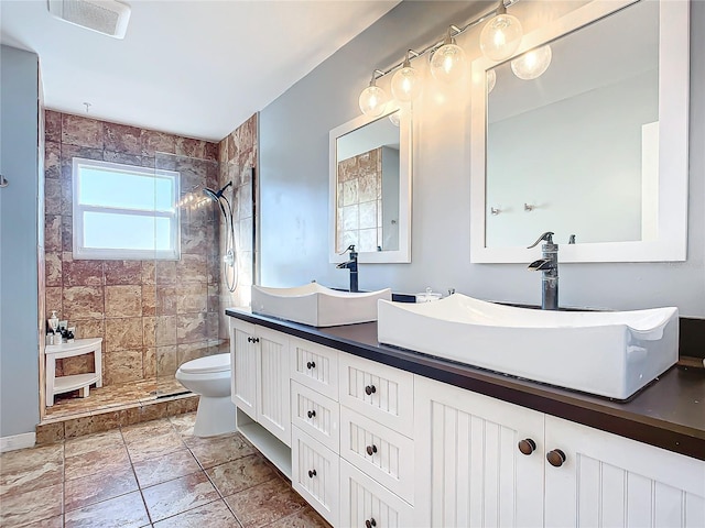 bathroom featuring vanity, toilet, and a tile shower