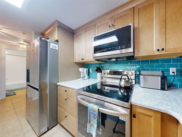 kitchen with light tile patterned flooring, stainless steel appliances, light brown cabinets, and tasteful backsplash