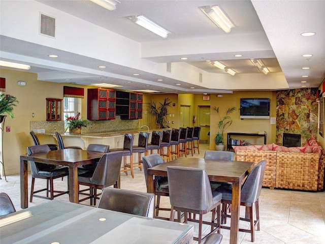 dining space featuring light tile patterned floors and a stone fireplace