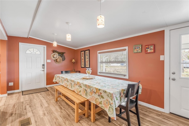 dining room featuring lofted ceiling, crown molding, a wealth of natural light, and light hardwood / wood-style flooring