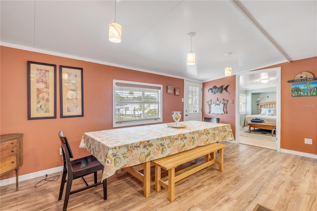 dining room with crown molding, light hardwood / wood-style floors, and vaulted ceiling