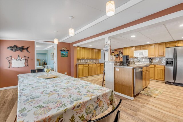 kitchen with hanging light fixtures, decorative backsplash, light hardwood / wood-style floors, appliances with stainless steel finishes, and a kitchen island