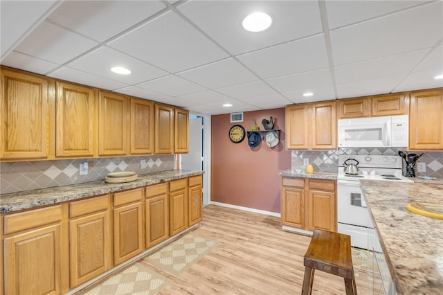 kitchen with light wood-type flooring, white appliances, tasteful backsplash, and light stone countertops