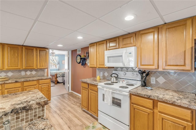 kitchen with a paneled ceiling, light wood-type flooring, white appliances, and backsplash