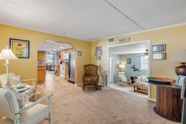 sitting room featuring ceiling fan, light colored carpet, and ornamental molding