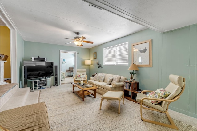 living room featuring carpet flooring, a textured ceiling, and ceiling fan