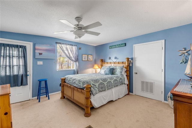 bedroom featuring a textured ceiling, ceiling fan, and light carpet