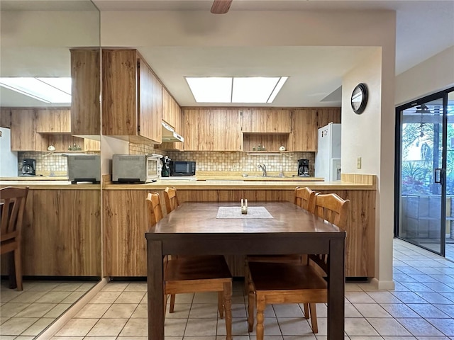 kitchen with sink, tasteful backsplash, white refrigerator with ice dispenser, kitchen peninsula, and light tile patterned floors