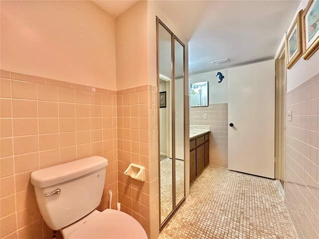 bathroom featuring tile patterned flooring, vanity, toilet, and tile walls