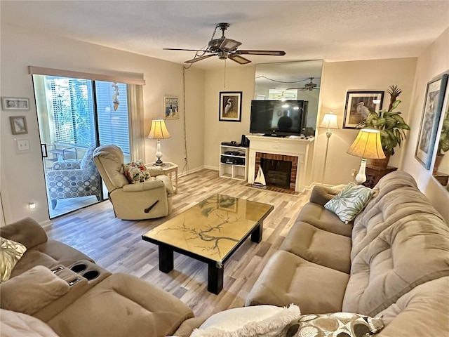 living room with a fireplace, a textured ceiling, light hardwood / wood-style floors, and ceiling fan