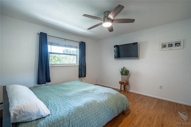 bedroom featuring ceiling fan, wood-type flooring, and a textured ceiling