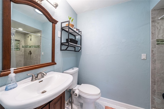 bathroom featuring tiled shower, toilet, and sink