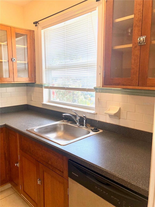 kitchen featuring stainless steel dishwasher, light tile patterned floors, sink, and tasteful backsplash