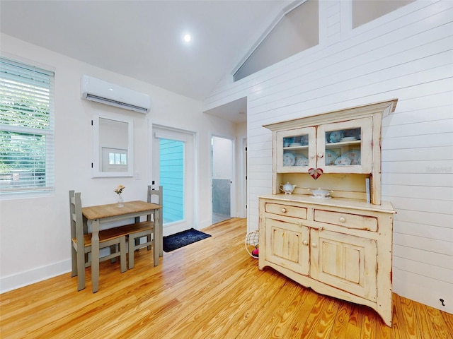 interior space featuring wood walls, light hardwood / wood-style flooring, high vaulted ceiling, and a wall mounted air conditioner