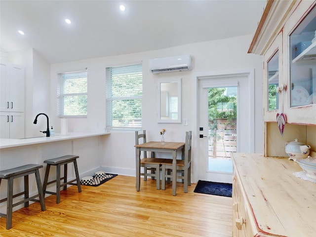 doorway to outside featuring light wood-type flooring, a wall unit AC, and a wealth of natural light