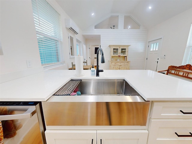 kitchen with an AC wall unit, dishwasher, and vaulted ceiling