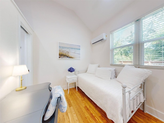 bedroom featuring hardwood / wood-style flooring, a wall mounted air conditioner, and vaulted ceiling