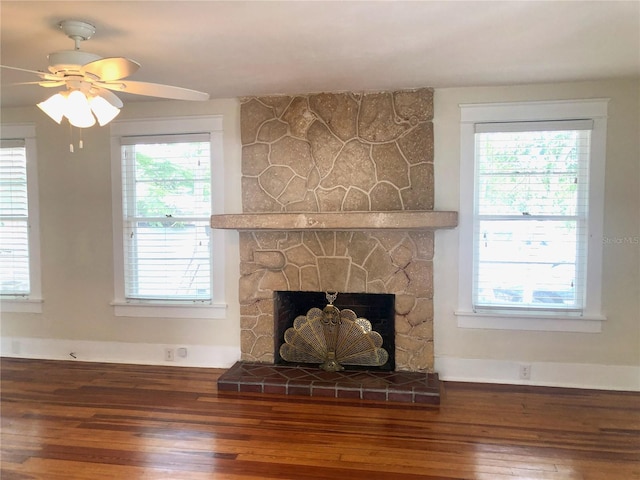 interior details with hardwood / wood-style flooring, a stone fireplace, and ceiling fan