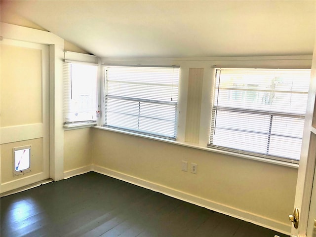 empty room with vaulted ceiling and hardwood / wood-style flooring