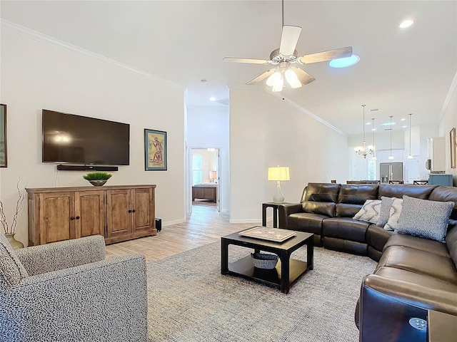 living area featuring ceiling fan with notable chandelier, baseboards, vaulted ceiling, ornamental molding, and light wood finished floors