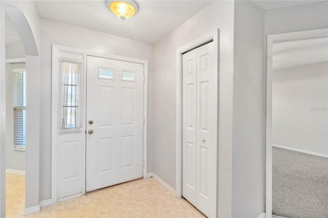 entryway featuring a textured ceiling and light colored carpet