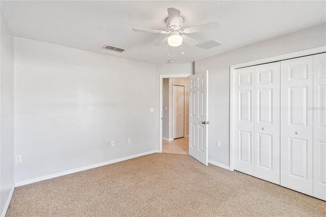 unfurnished bedroom featuring ceiling fan, a closet, and light colored carpet