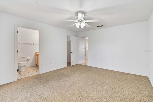 unfurnished bedroom featuring ceiling fan, a spacious closet, ensuite bathroom, light colored carpet, and a closet