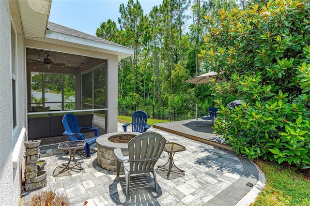 view of patio with a fire pit, a sunroom, ceiling fan, and a deck