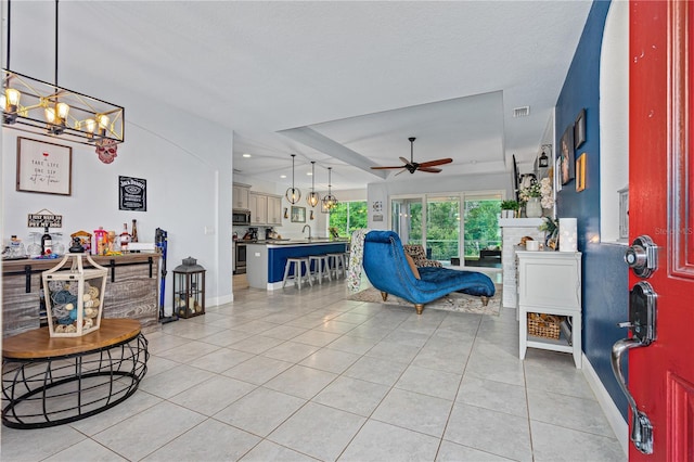 tiled foyer entrance with a textured ceiling, sink, and ceiling fan with notable chandelier