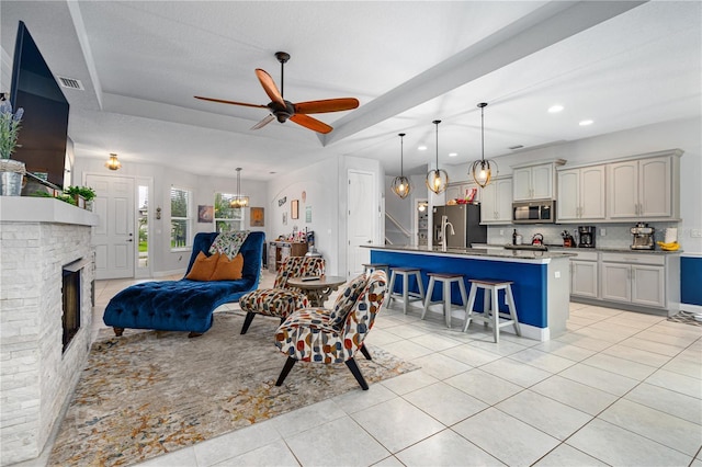 tiled living room featuring ceiling fan, a fireplace, and a textured ceiling