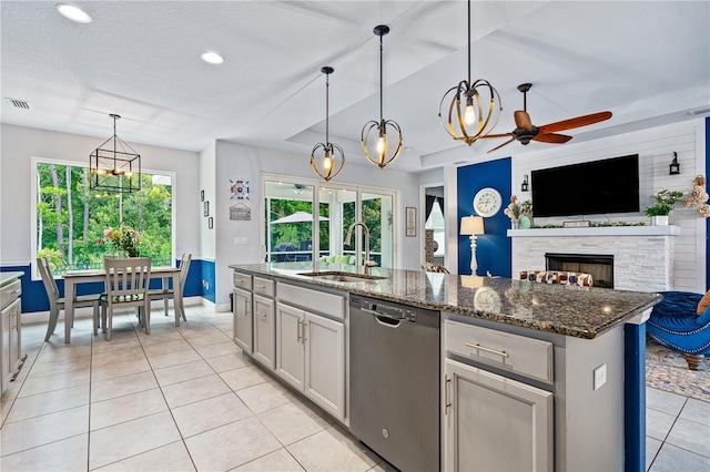 kitchen with ceiling fan, dishwasher, sink, hanging light fixtures, and a center island with sink