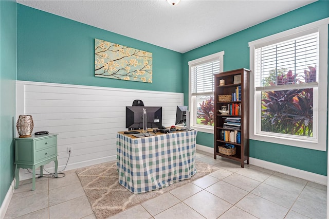 office featuring wood walls, light tile patterned floors, and a textured ceiling