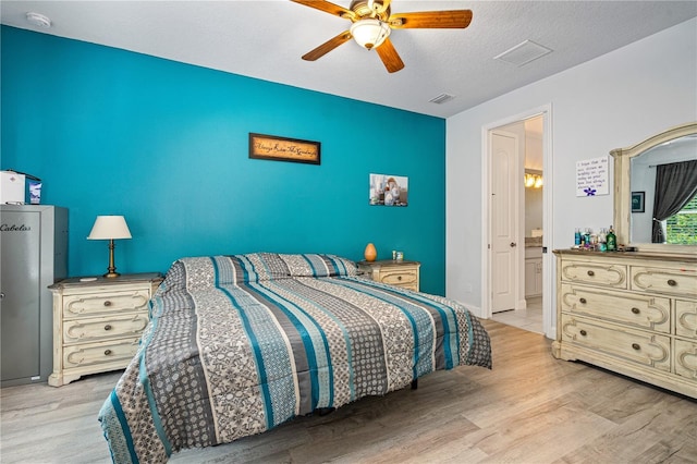 bedroom featuring ensuite bathroom, ceiling fan, a textured ceiling, and light wood-type flooring