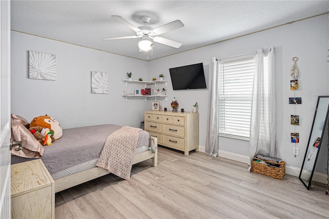 bedroom featuring ceiling fan, light hardwood / wood-style floors, and a textured ceiling