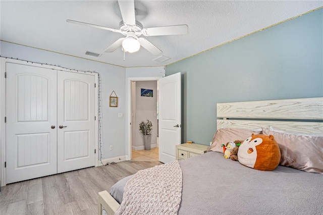 bedroom with ceiling fan, light wood-type flooring, a textured ceiling, and a closet