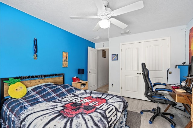 bedroom featuring ceiling fan, light wood-type flooring, a textured ceiling, and a closet