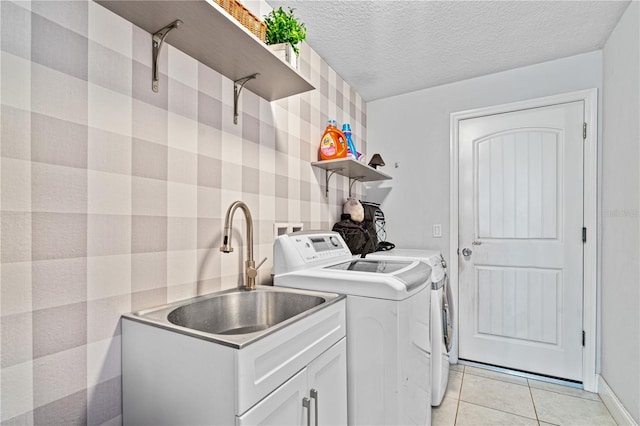 washroom with sink, independent washer and dryer, a textured ceiling, and light tile patterned flooring