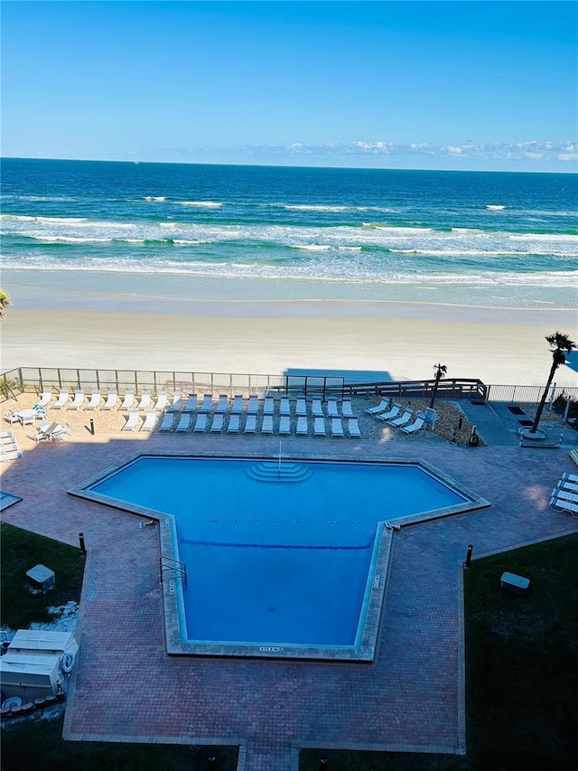 view of pool with a water view and a beach view