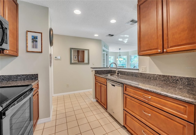 kitchen featuring sink, stainless steel appliances, dark stone countertops, a textured ceiling, and light tile patterned floors