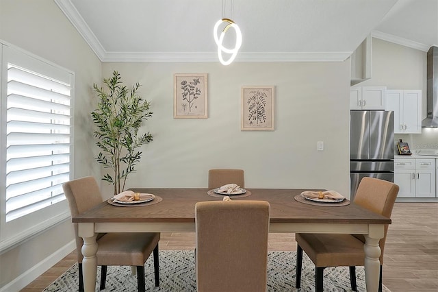 dining area with light wood-type flooring, vaulted ceiling, and ornamental molding