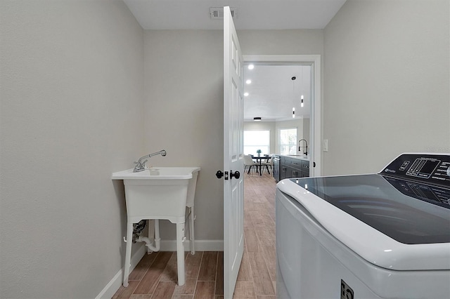 laundry room with hardwood / wood-style flooring, sink, and washer / dryer