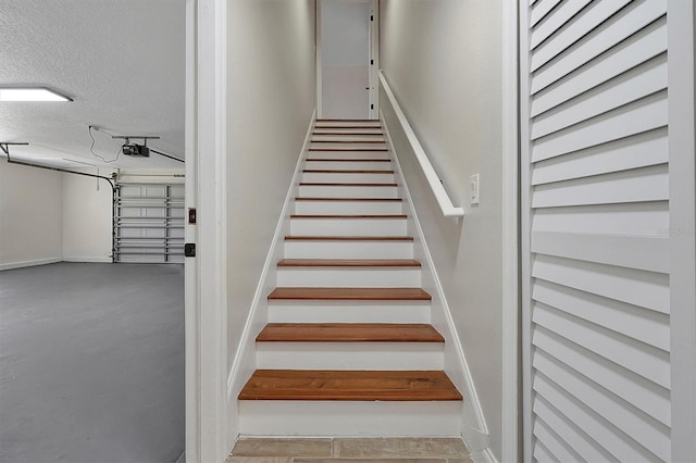 stairs with concrete flooring and a textured ceiling