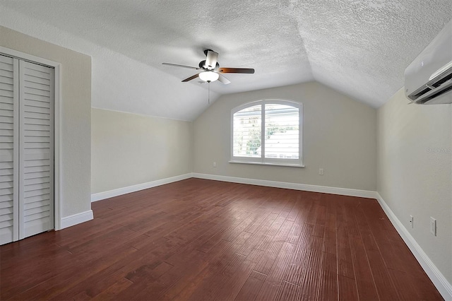 bonus room with lofted ceiling, dark wood-type flooring, ceiling fan, a textured ceiling, and a wall unit AC